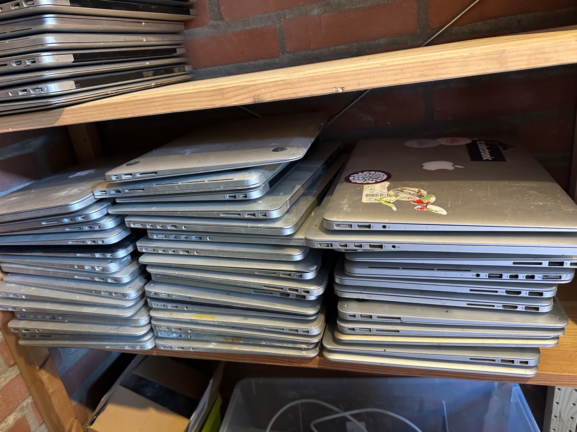 Stapels oudere MacBooks op een stelling bij iMac and More, ingekocht uit een bedrijfsomgeving