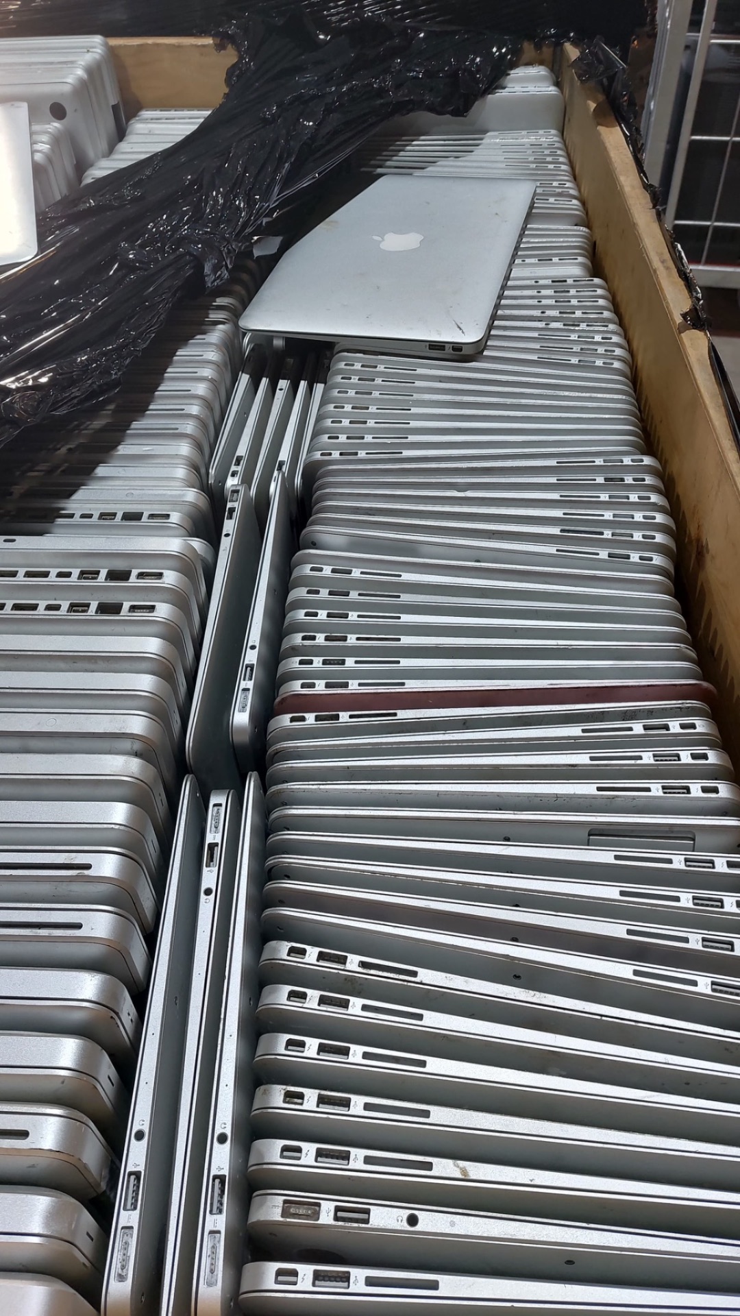 Grote partij MacBooks in een krat — voorbeeld van een complete zakelijke Apple-vloot ingekocht door iMac and More